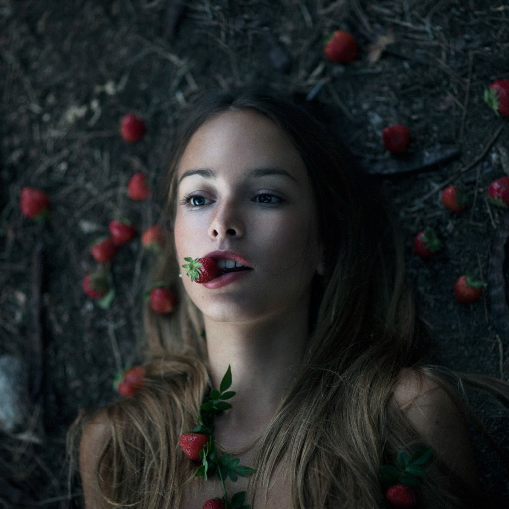 Девушка лежит на земле среди клубники