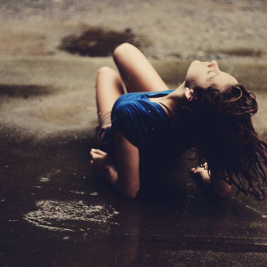 Девушка лежит на асфальте под дождем