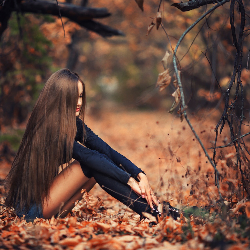 Девушка сидит на осенней листве