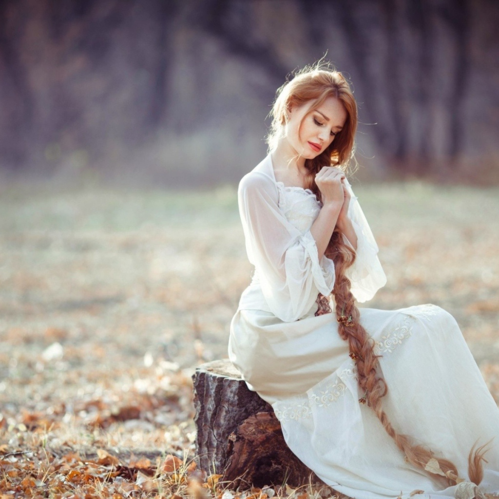 Девушка с косой сидит на пеньке