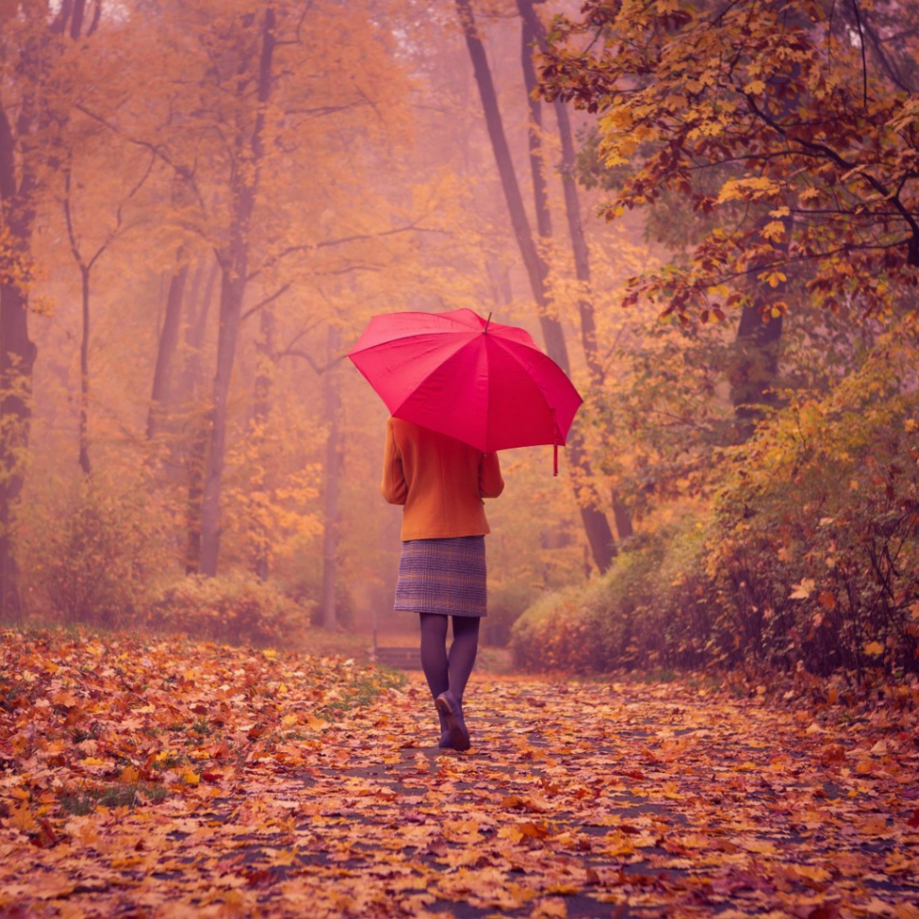 Девушка с красным зонтом идет по аллее