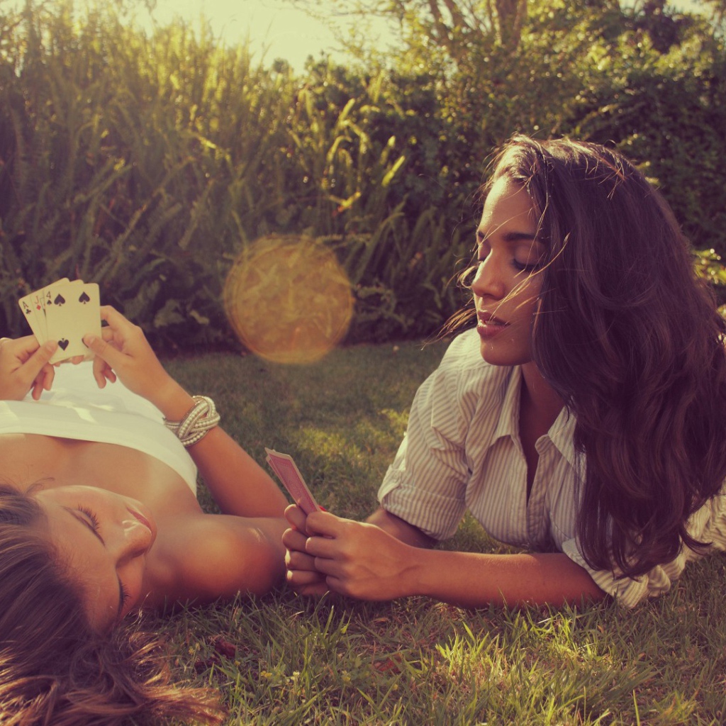 Девушки играют в карты на газоне