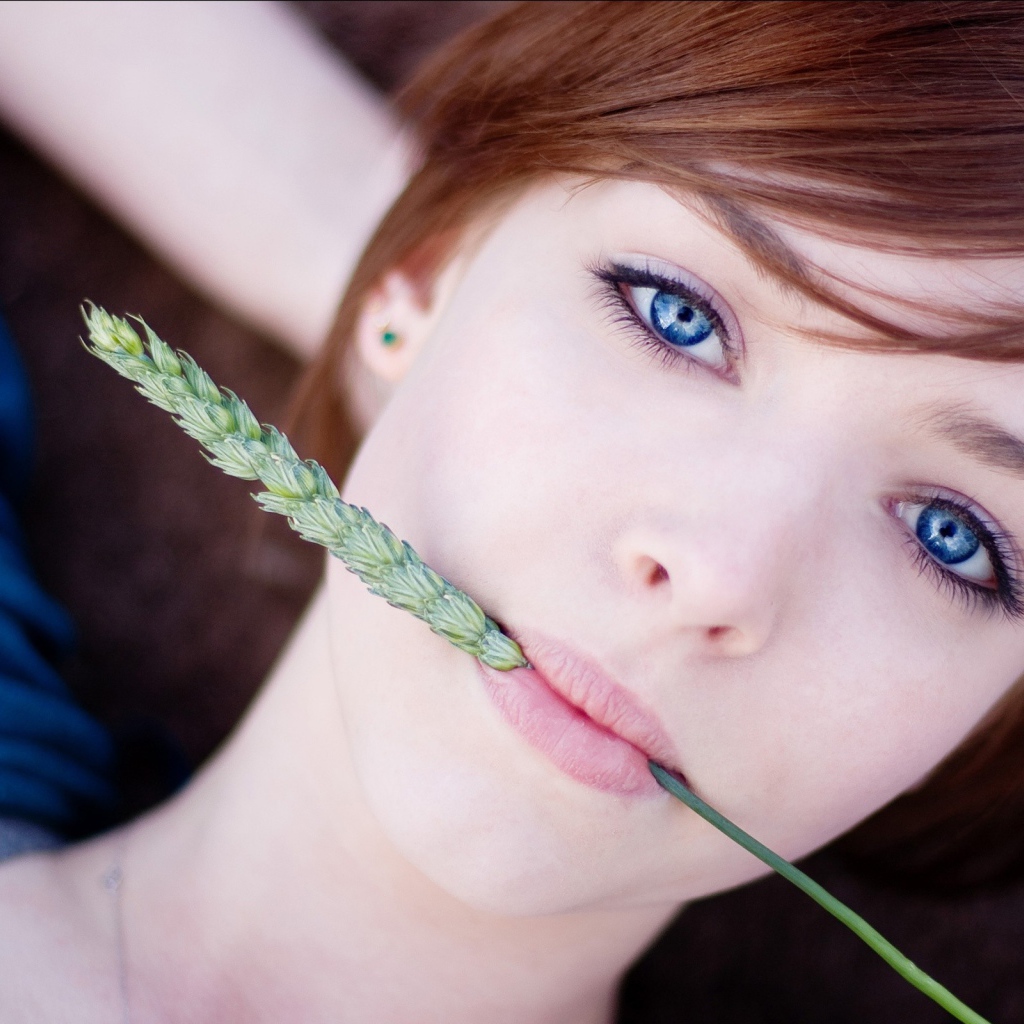 Зеленый колосок во рту у девушки