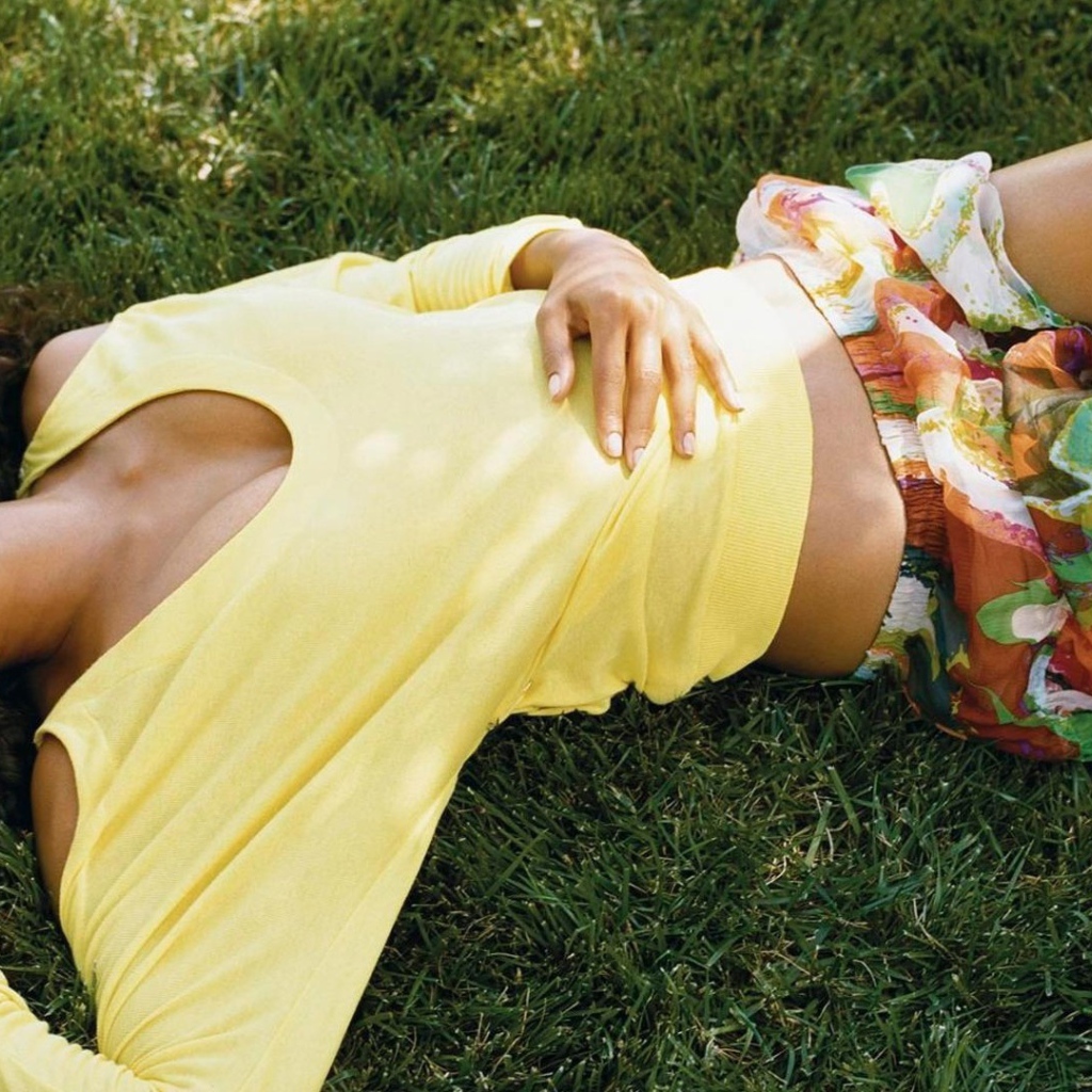 Мулатка в желтой футболке лежит на траве