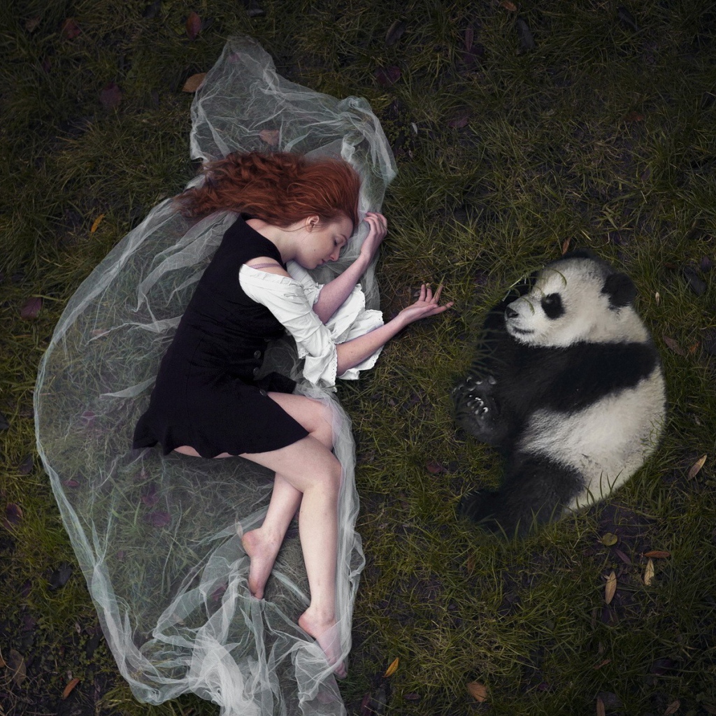 Девушка и панда лежат рядом на траве
