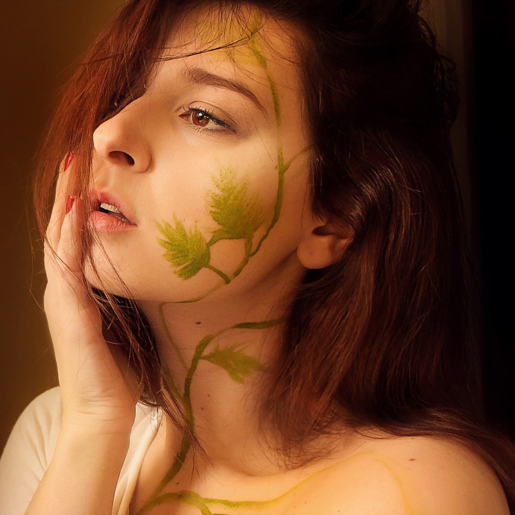 Рисунок зеленых листьев на лице и шее девушки