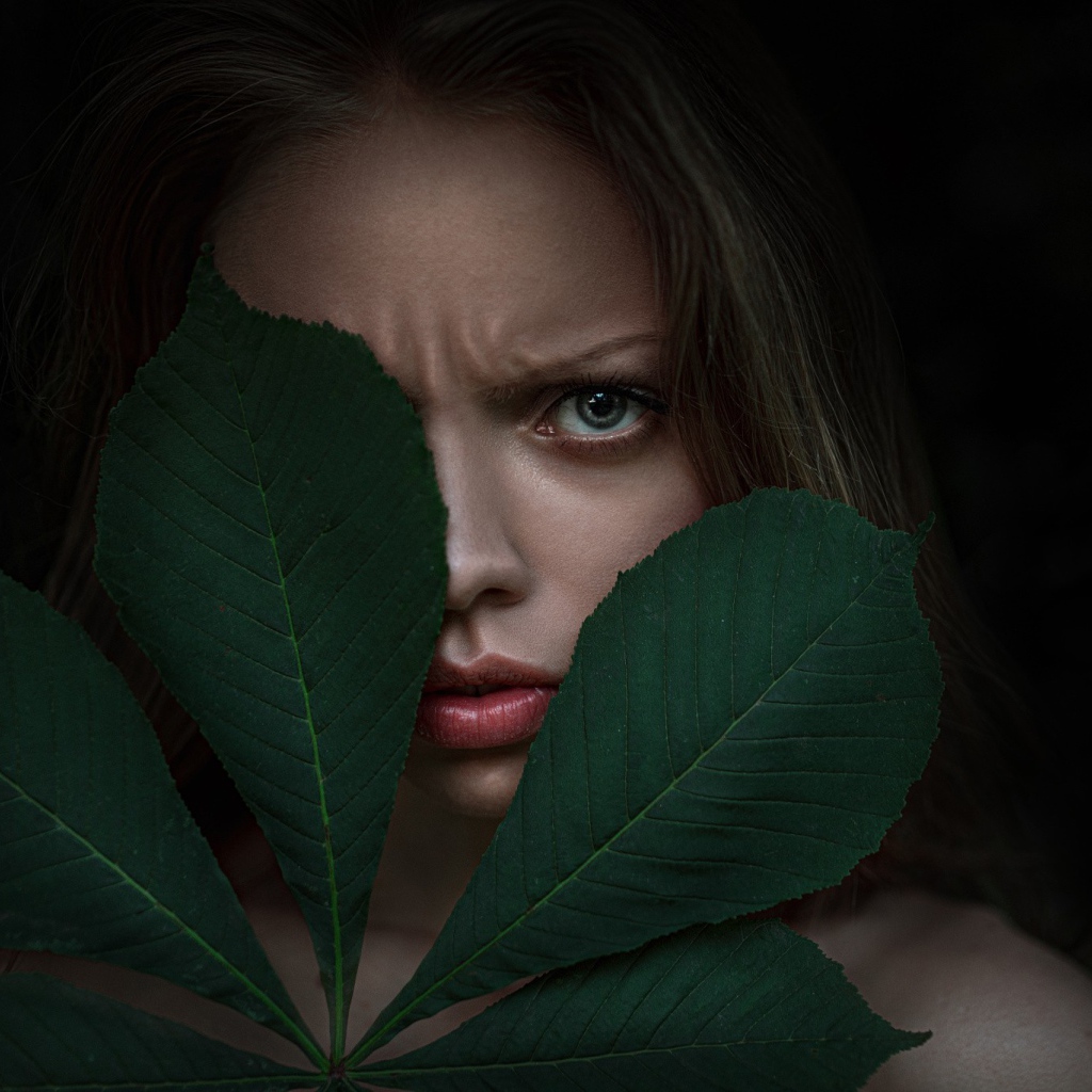 Девушка прикрыла лицо листьями каштана