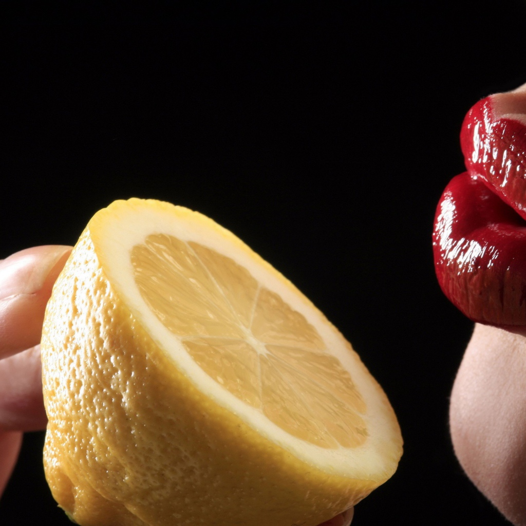 Девушка поднесла лимон к губам