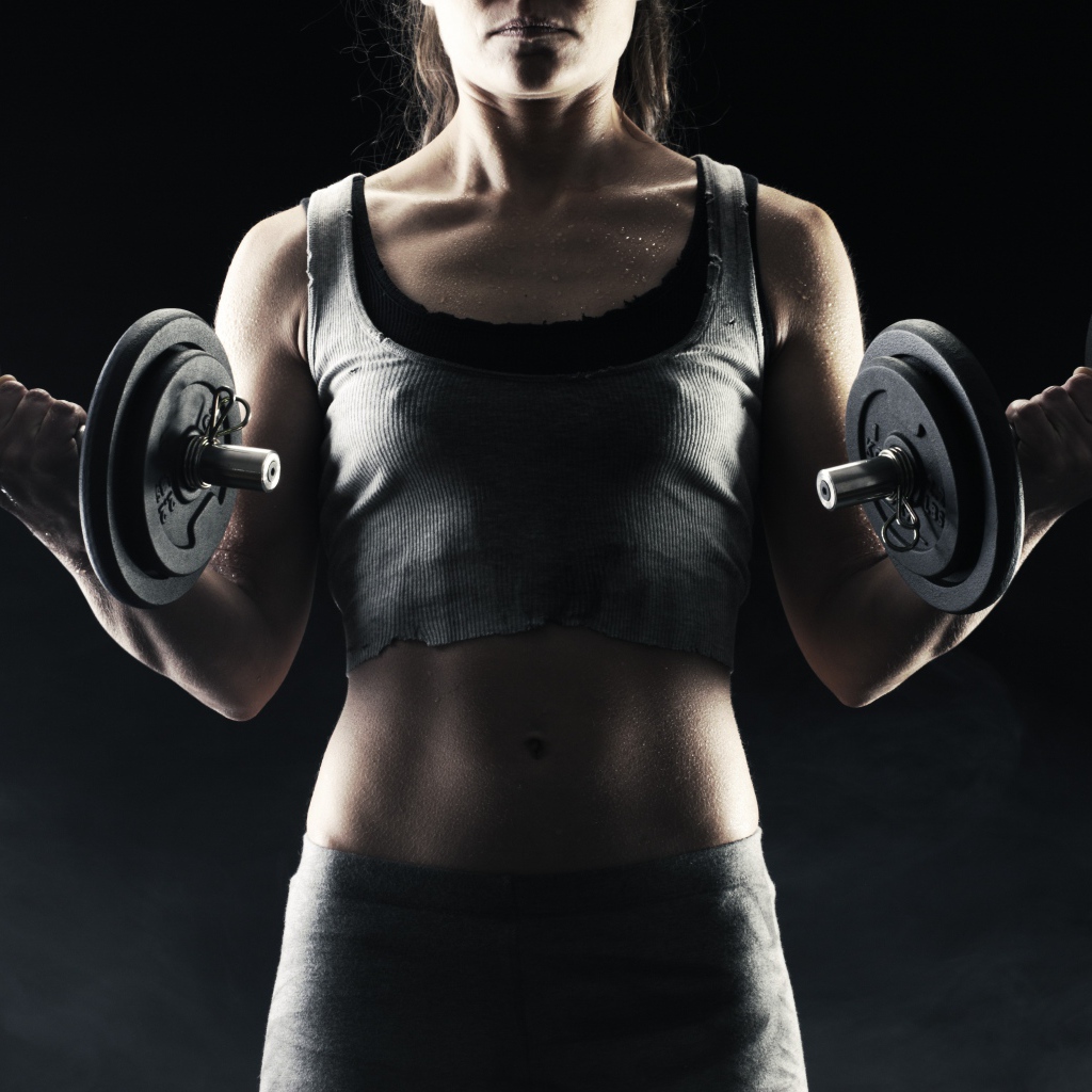 Спортивная девушка с гантелями в руках