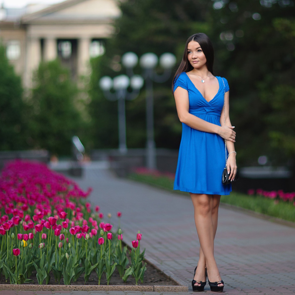 Брюнетка в голубом платье у клумбы с тюльпанами