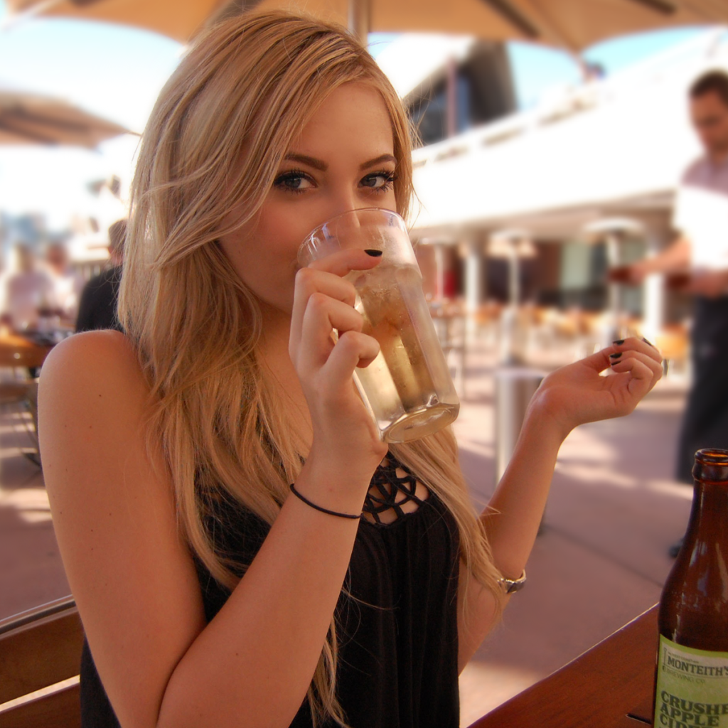 Девушка пьет из стакана в кафе