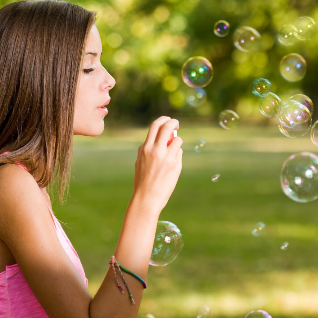 Девушка в розовой футболке запускает мыльные пузыри