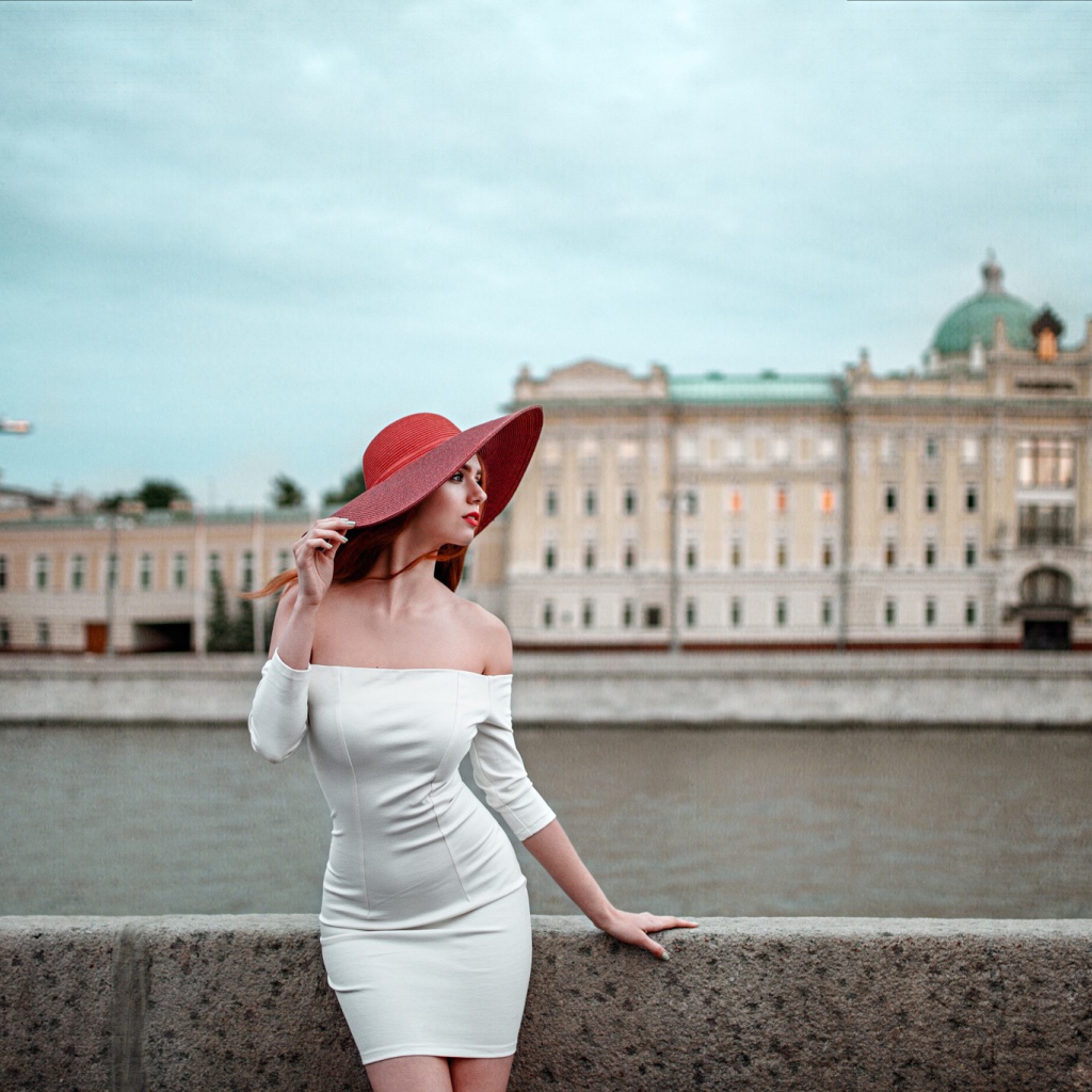 Девушка в белом платье и красной шляпе на набережной