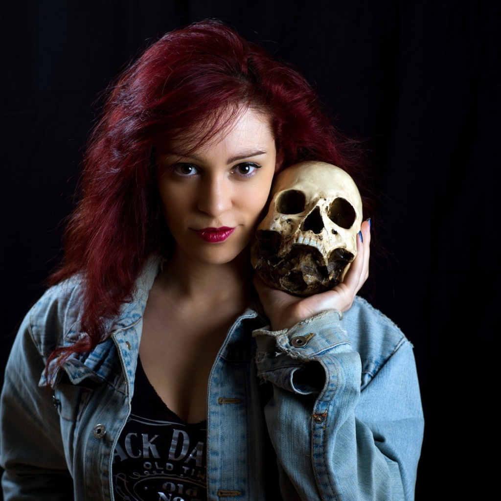 Девушка в джинсовой куртке держит череп на плече
