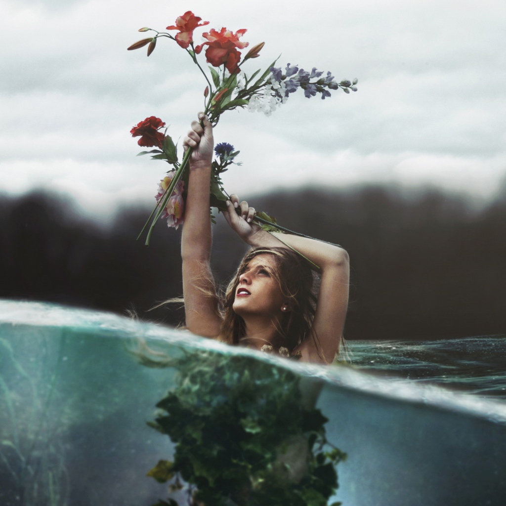 Девушка в воде стоит вытянув руку с букетом