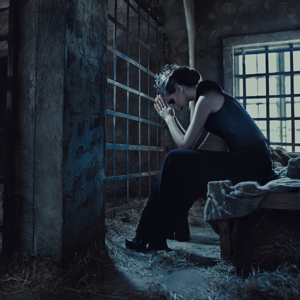 Девушка сидит за решеткой в тюрьме