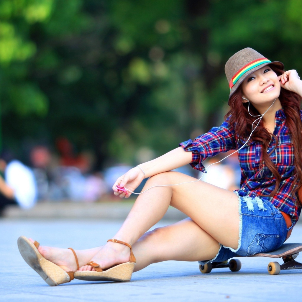 Девушка сидит на скейтборде