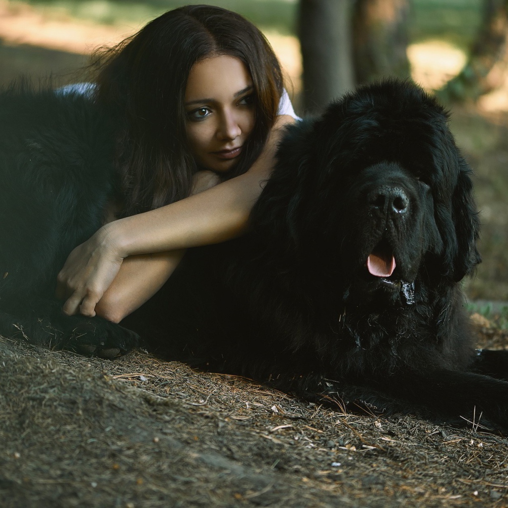 Девушка лежит на большой черной собаке