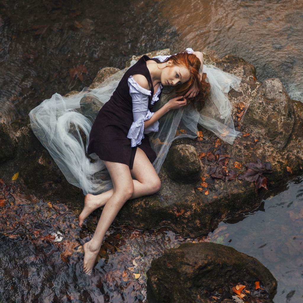 Девушка лежит на камне среди воды