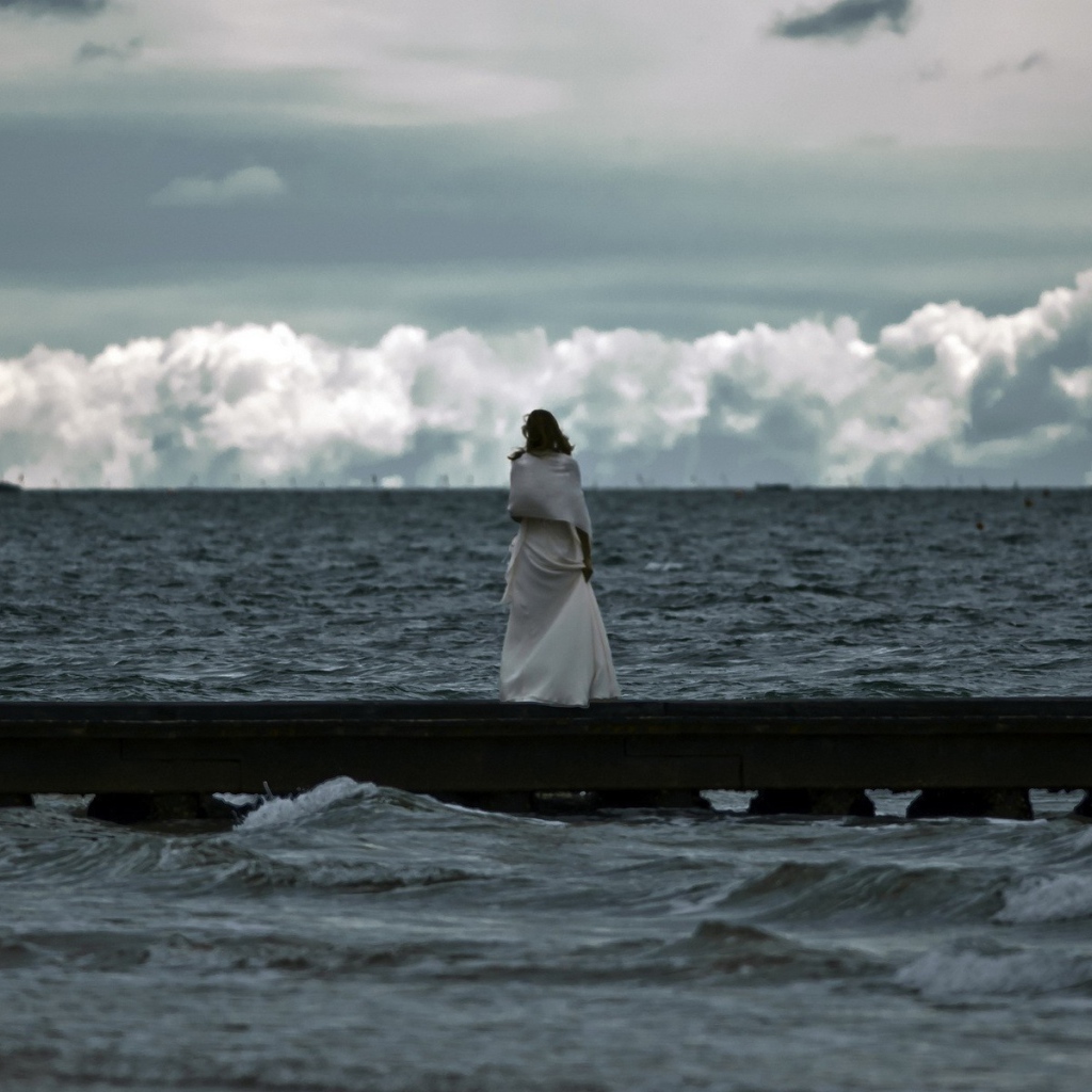 Девушка смотрит на свинцовые воды моря