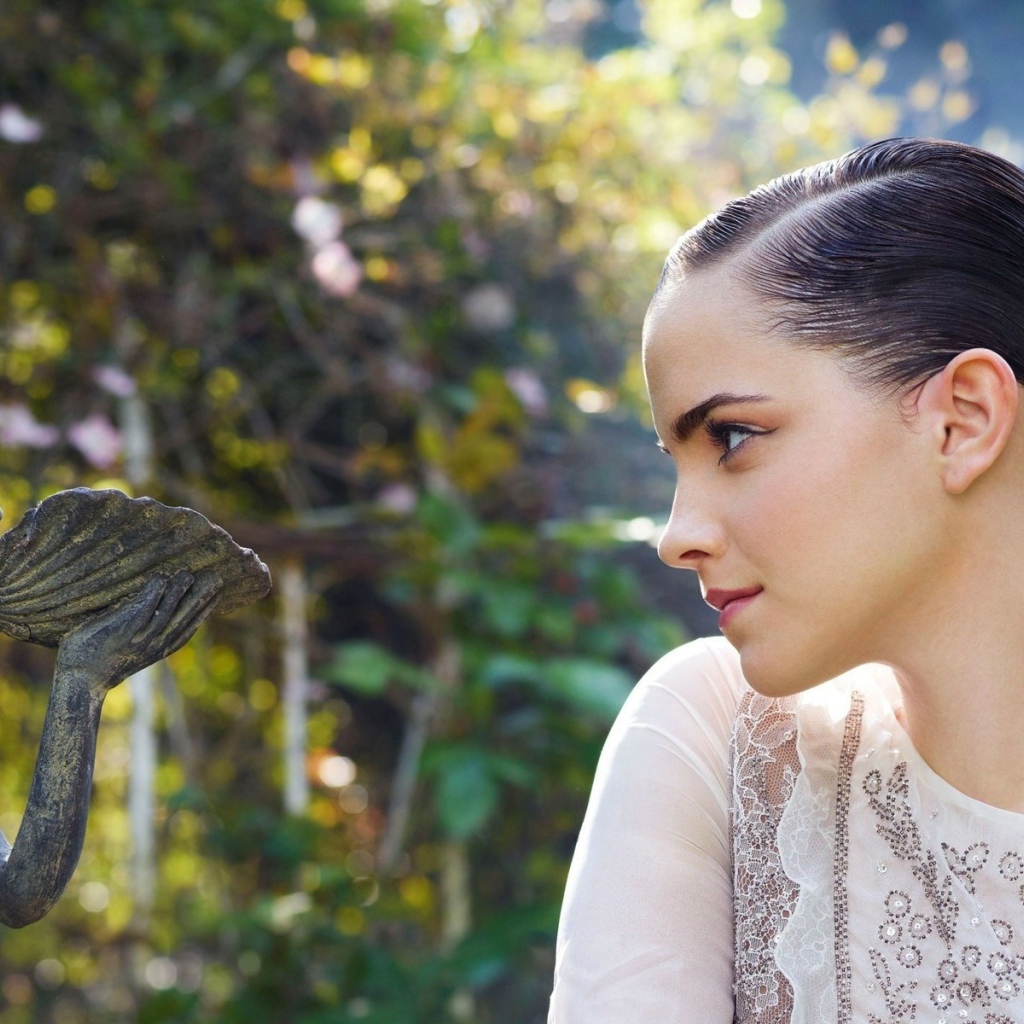 Девушка смотрит на скульптуру в саду