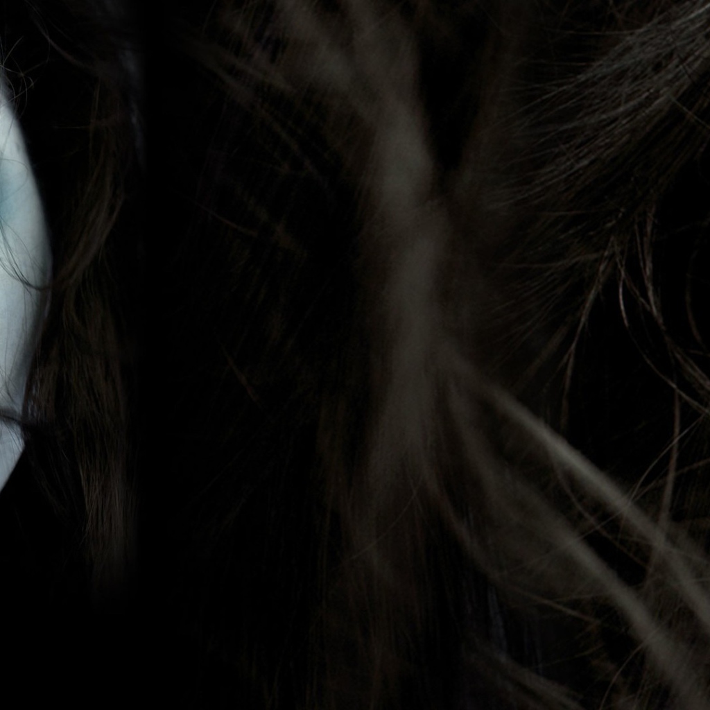 Лицо девушки среди волос на темном фоне