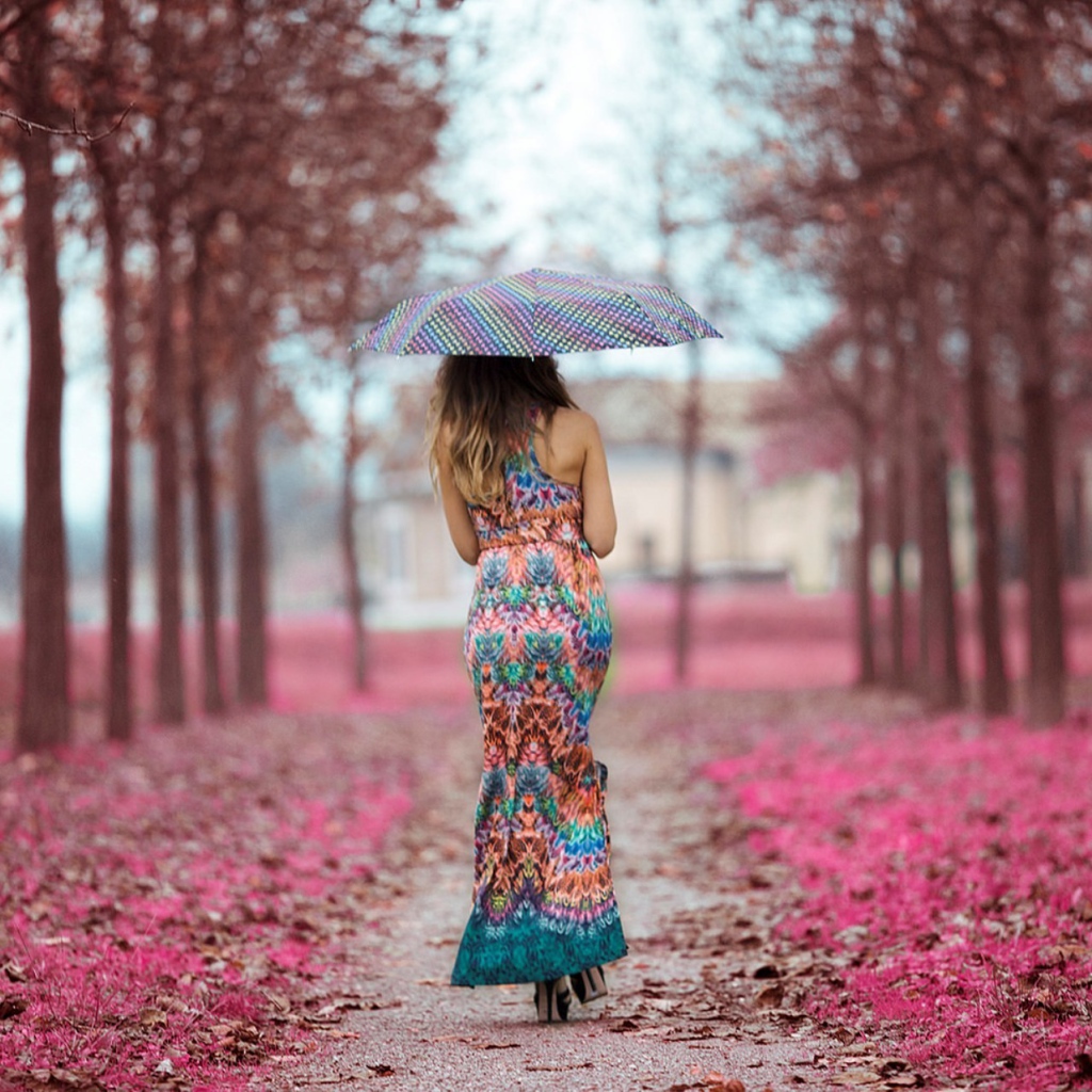 Девушка под зонтом в красивом платье идет по аллее