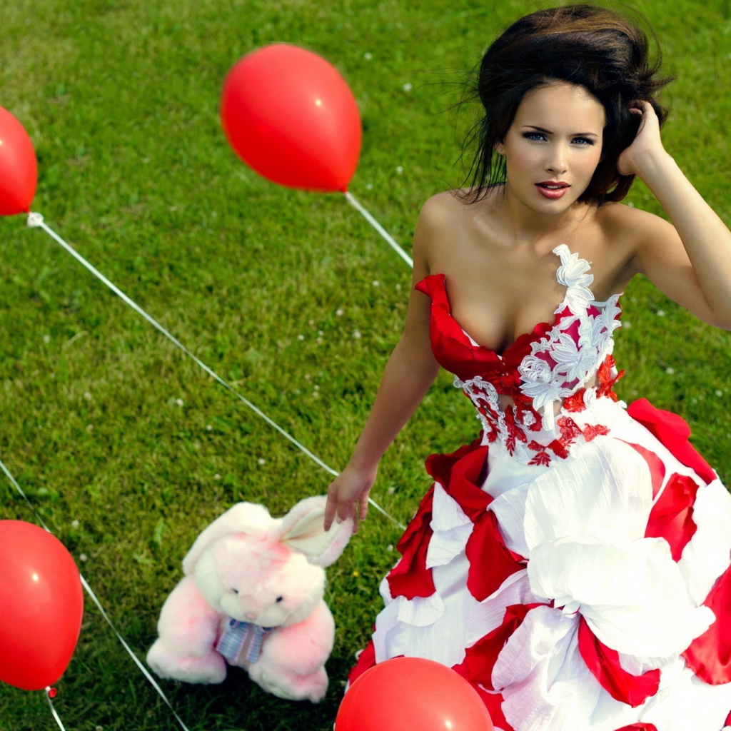 Девушка с игрушкой среди красных воздушных шариков