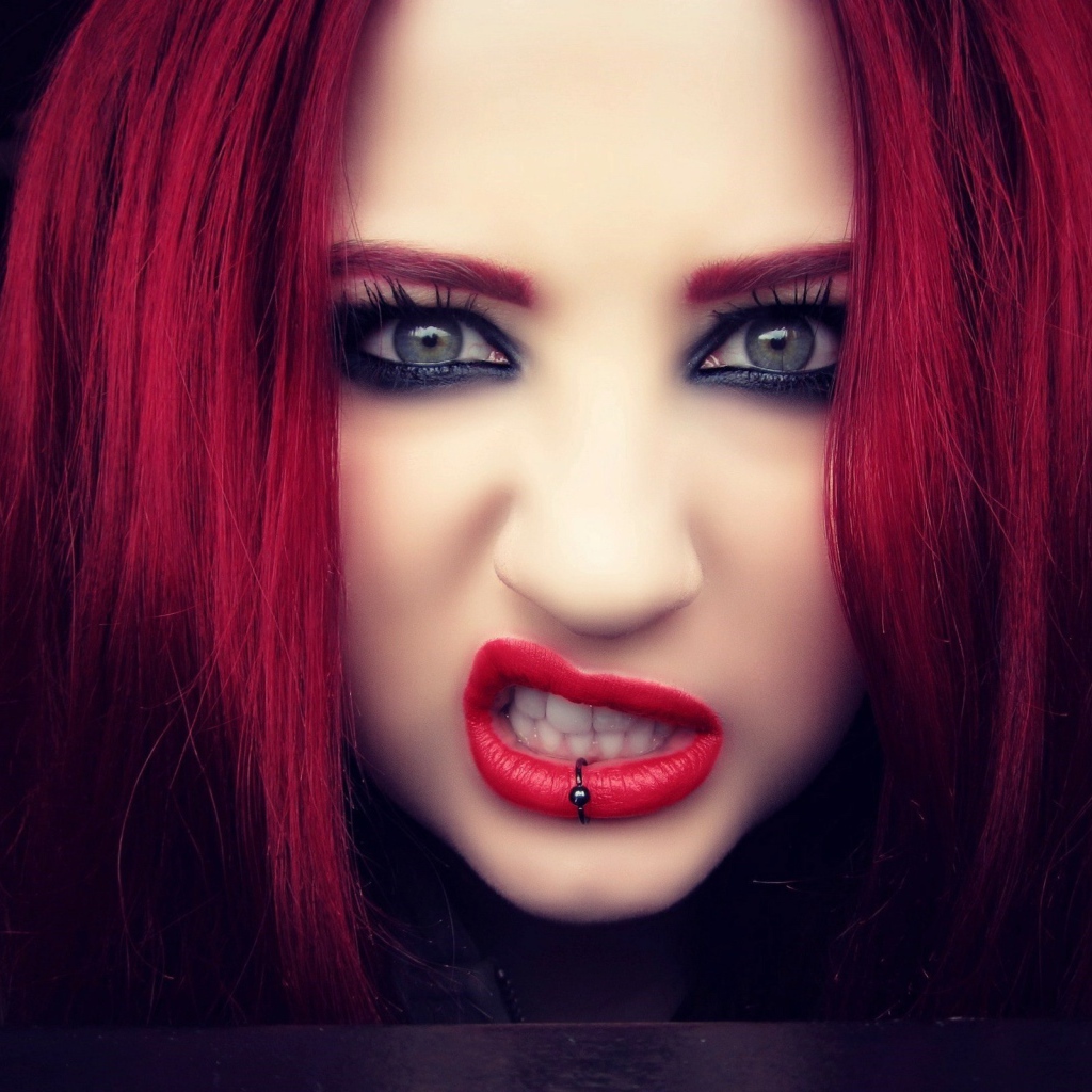 Девушка с красными волосами показывает зубы