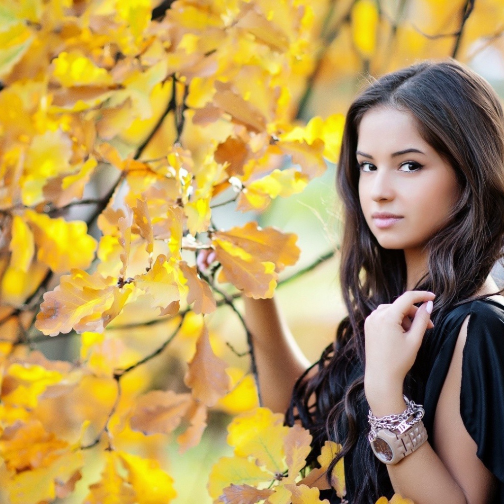 Молодая брюнетка у осеннего дерева