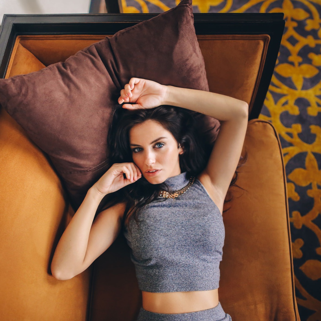 Модель Aurela Skandaj лежит на диване