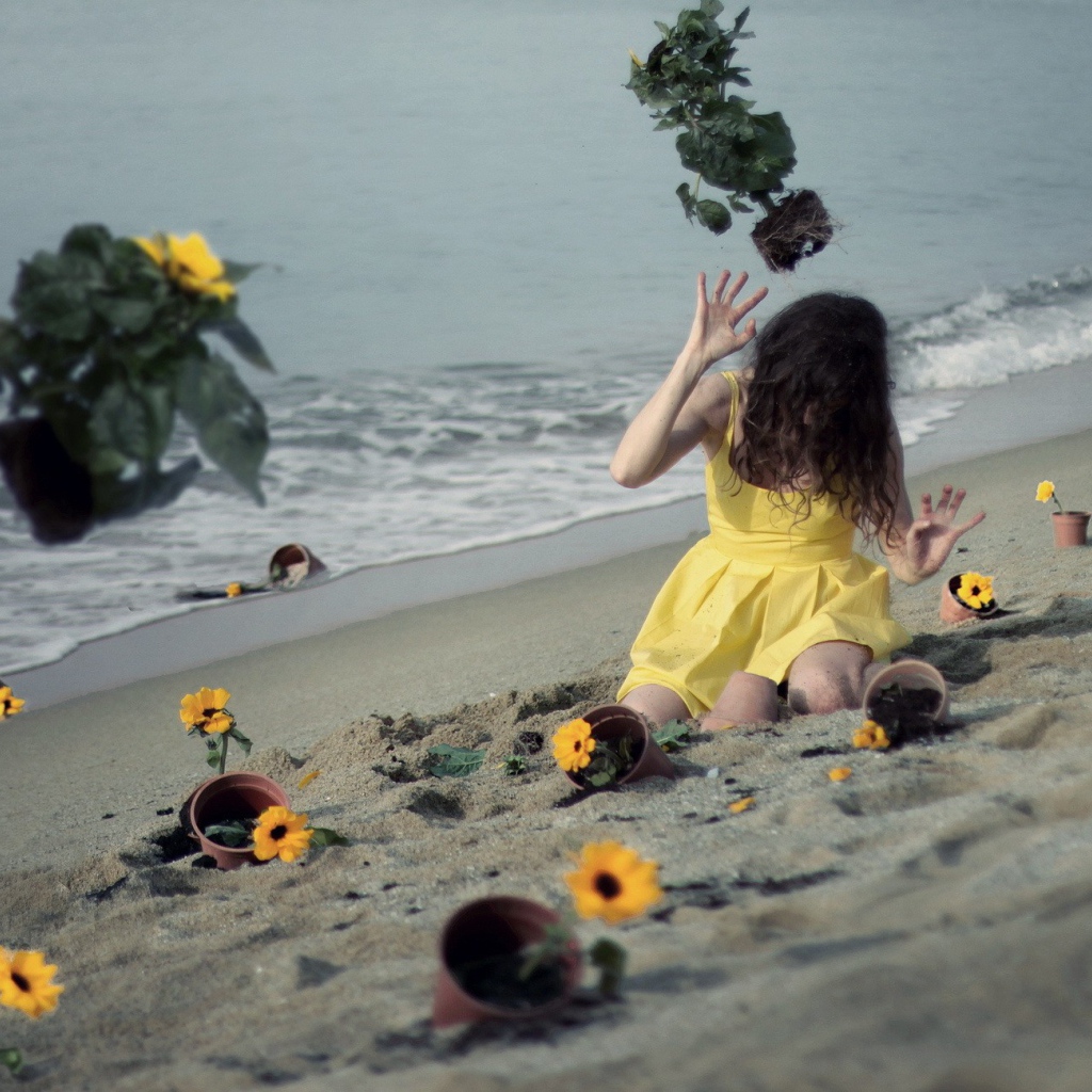 Модель в желтом платье среди цветов на пляже