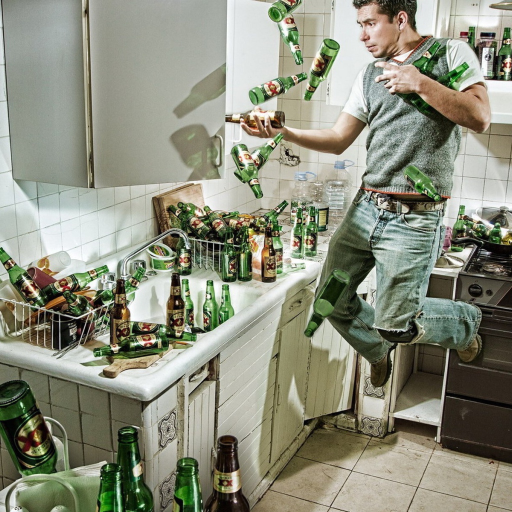 Мужчина среди бутылок пива на кухне