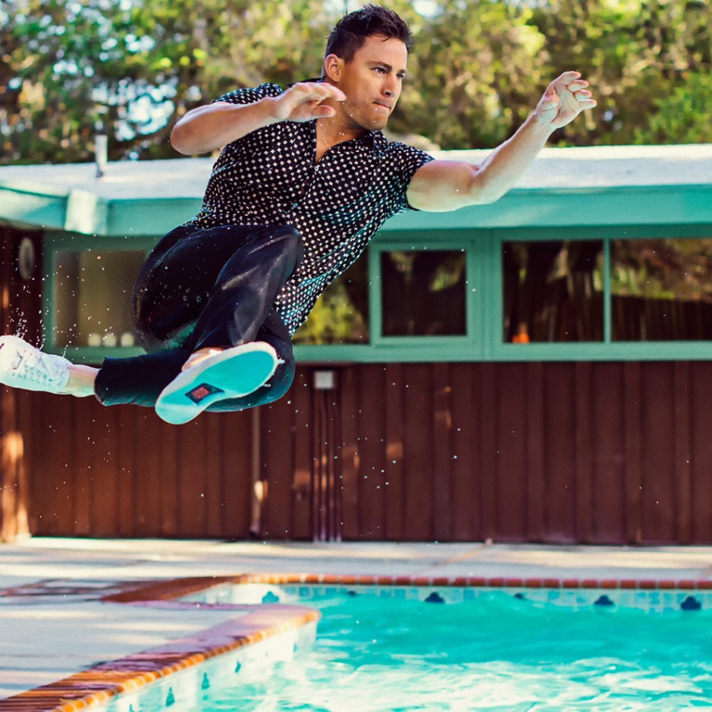 Мужчина прыгает в бассейн в одежде