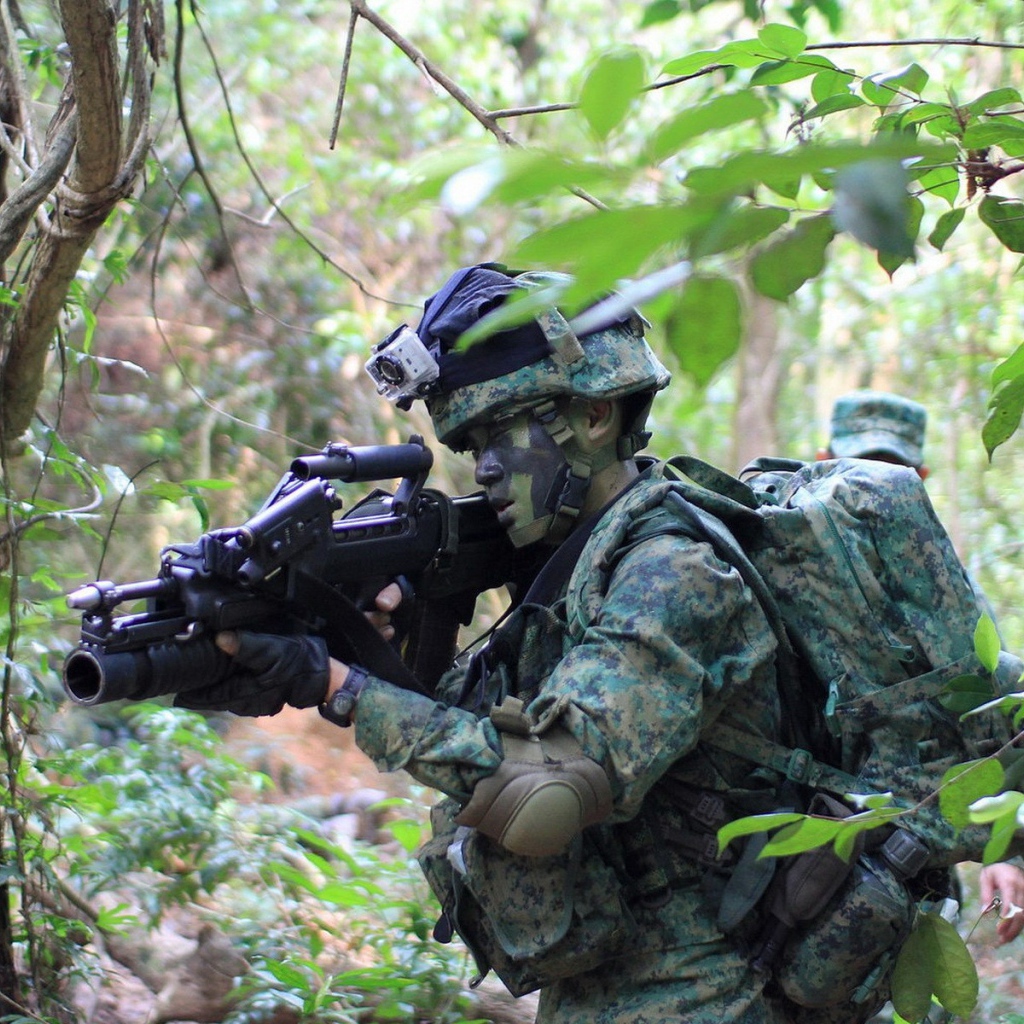 Солдат в камуфляже идет по лесу