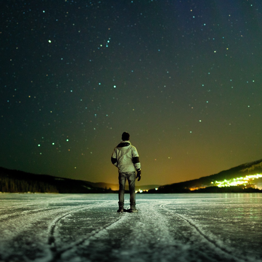 Мужчина на льду смотрит на звезды