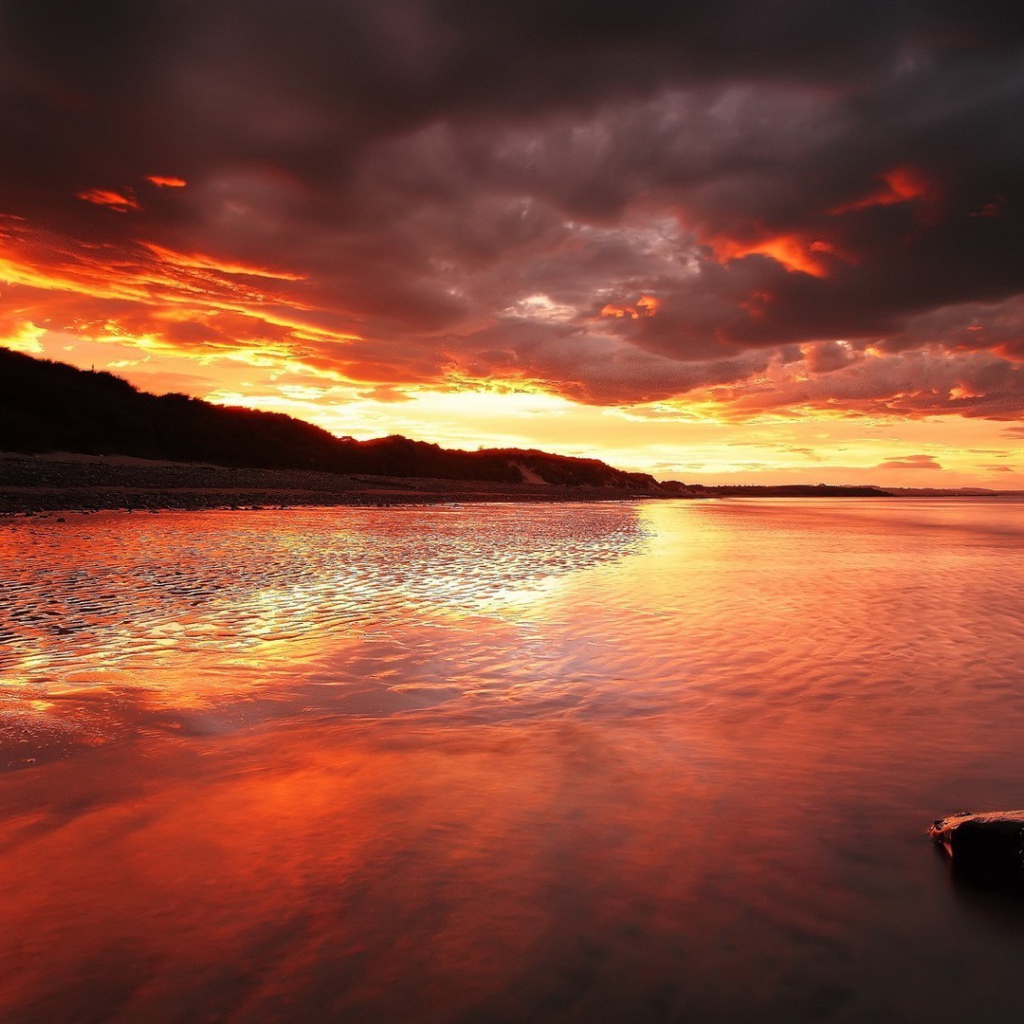 Камень на мелководье на фоне красного заката