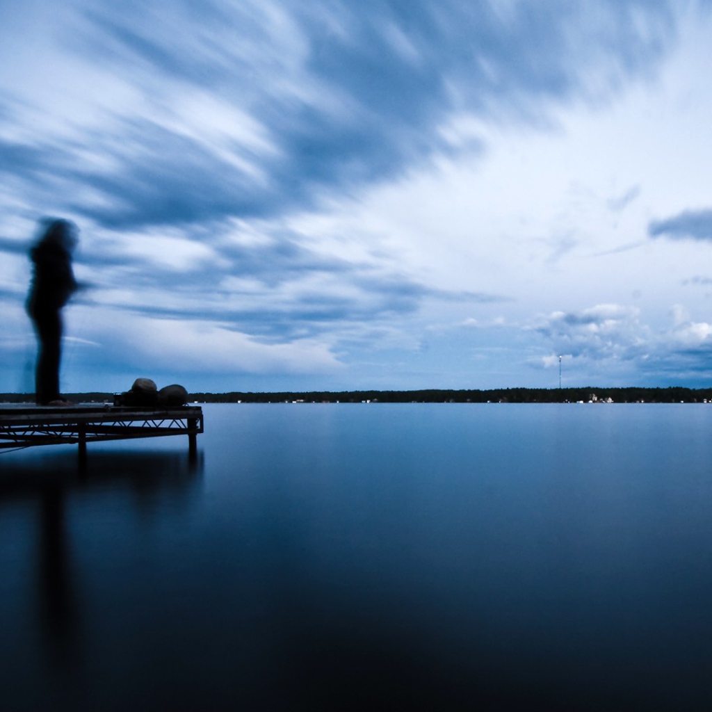 Силуэт человека на пристани у озера