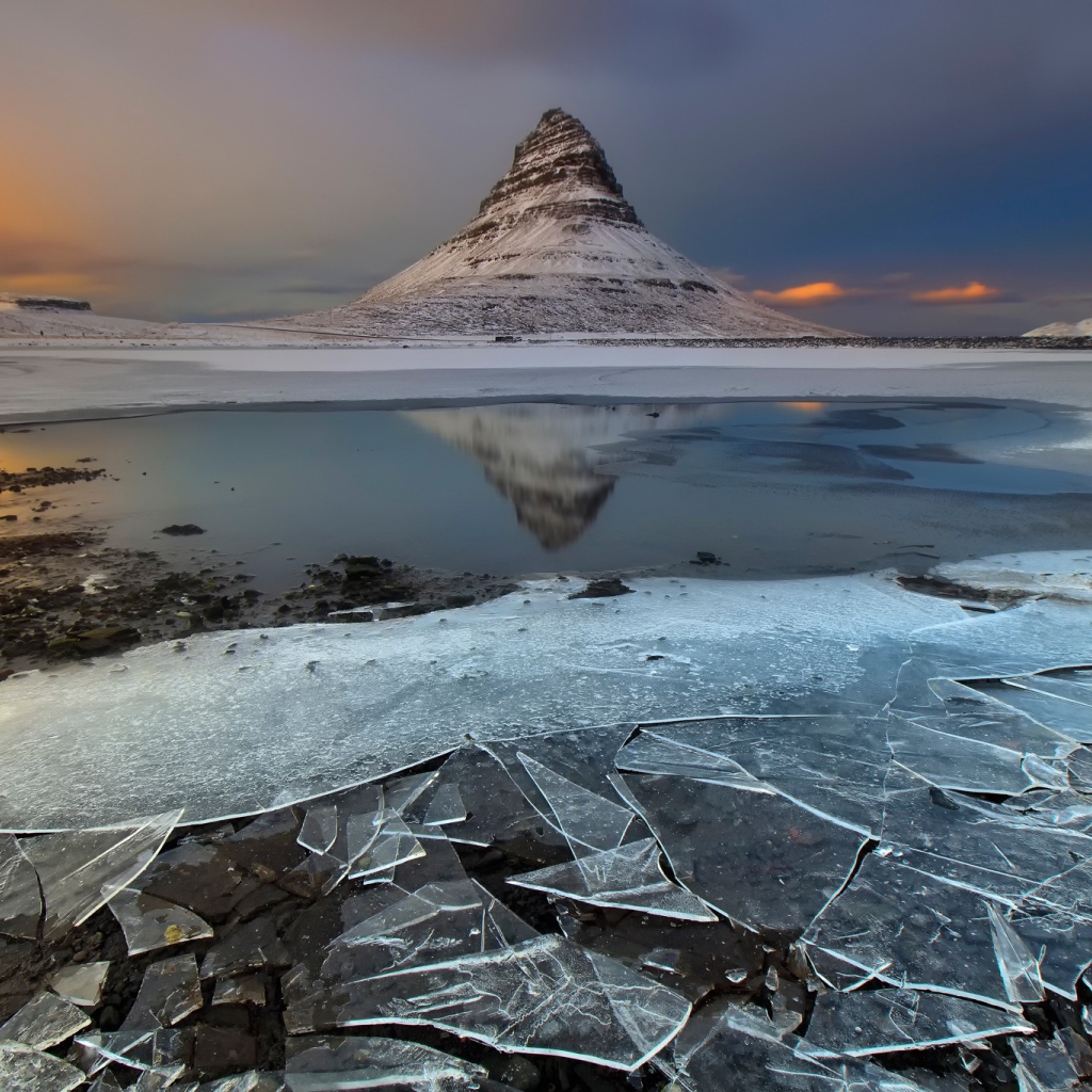 Тонкий лед озера на фоне горы