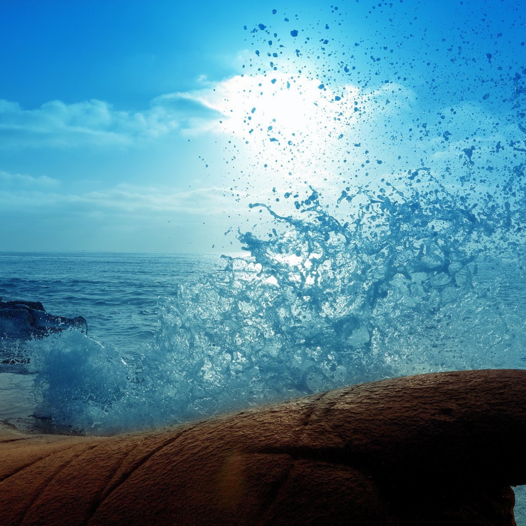 Голубая волна разбилась о камень на берегу