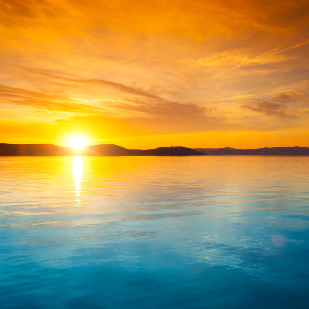 Оранжевое небо над голубой водой на закате