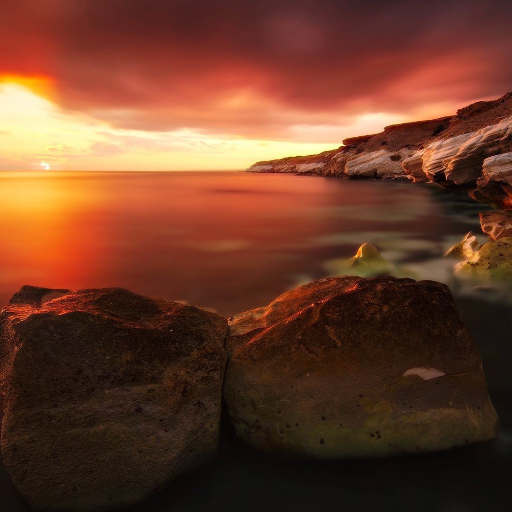 Два больших камня на берегу моря на закате