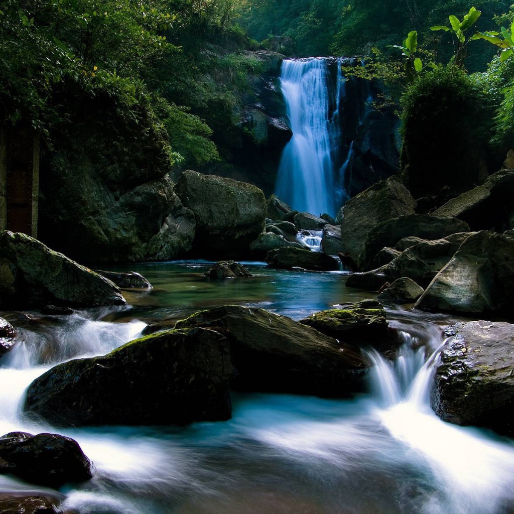 Голубой водопад позади камней на реке