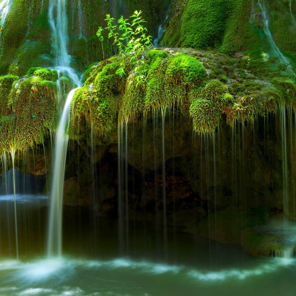 Вода стекает по покрытым мхом скалам