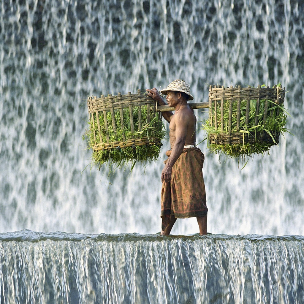 Крестьянин с корзинами идет по водопаду