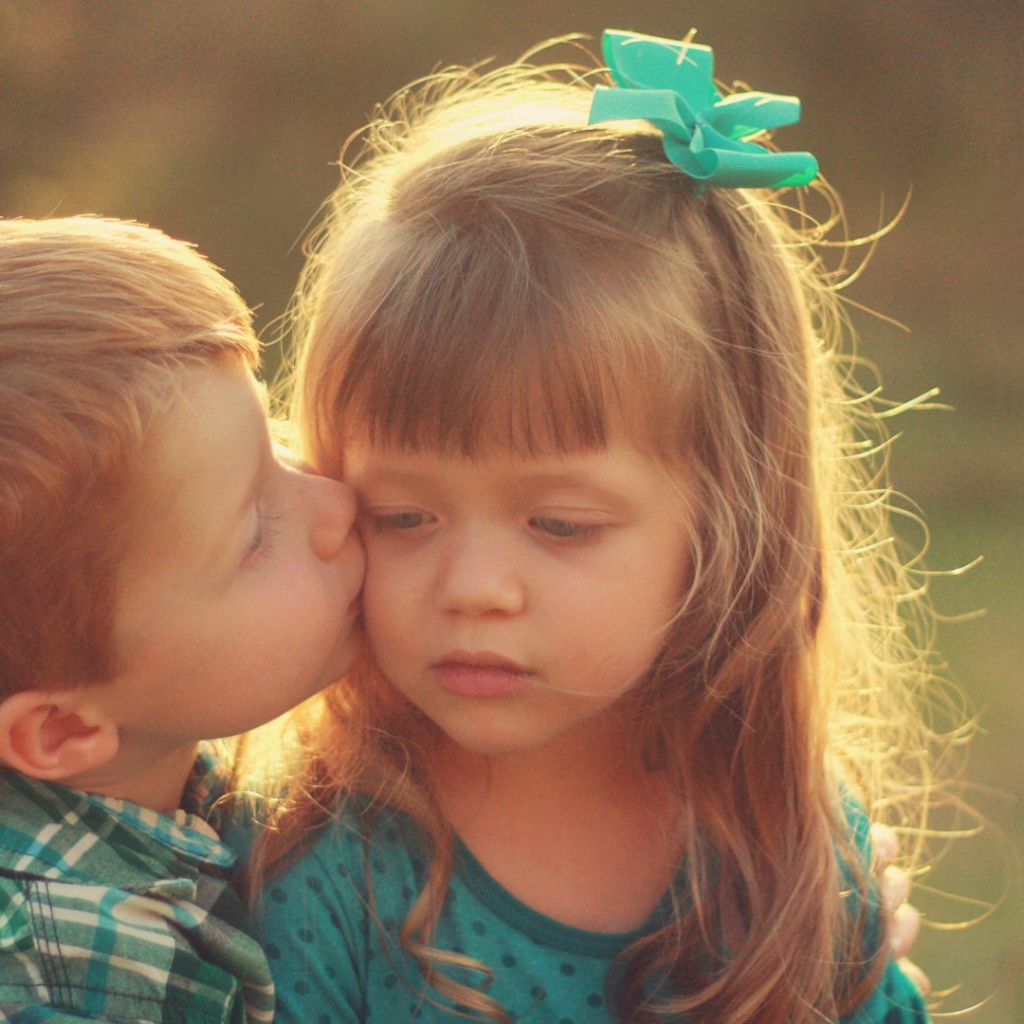 Мальчик целует сестренку в щеку