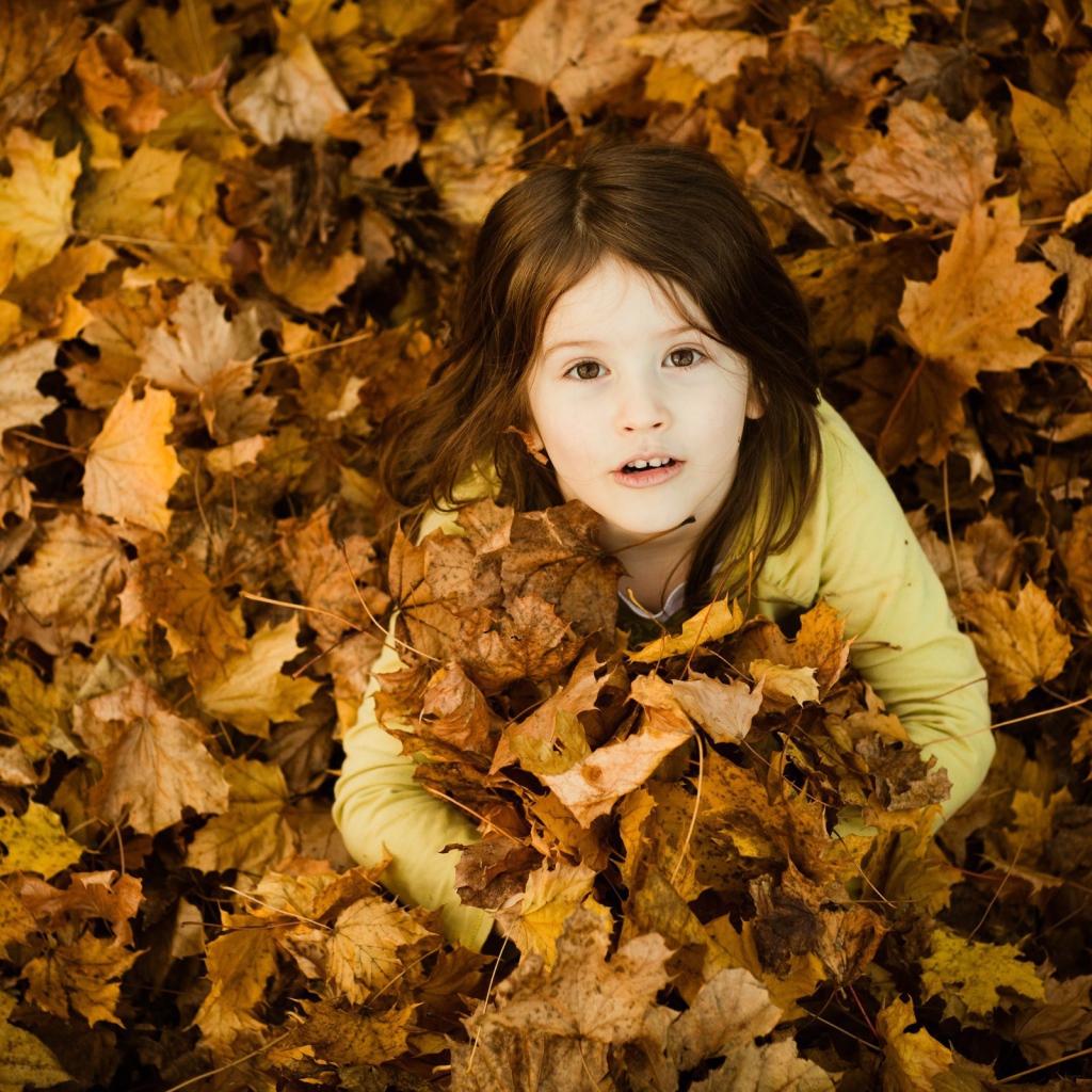 Девочка зарылась в опавшие листья