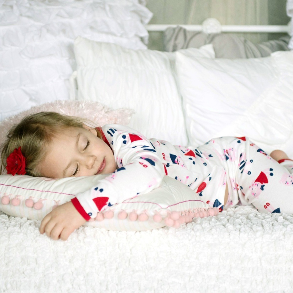 Девочка в пижаме спит на кровати