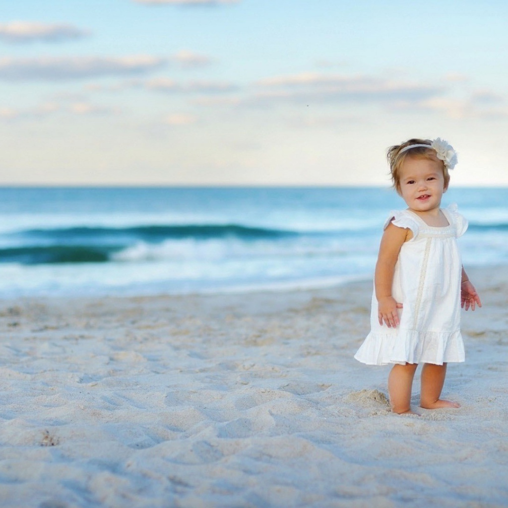 Девочка в белом платье на песке пляжа