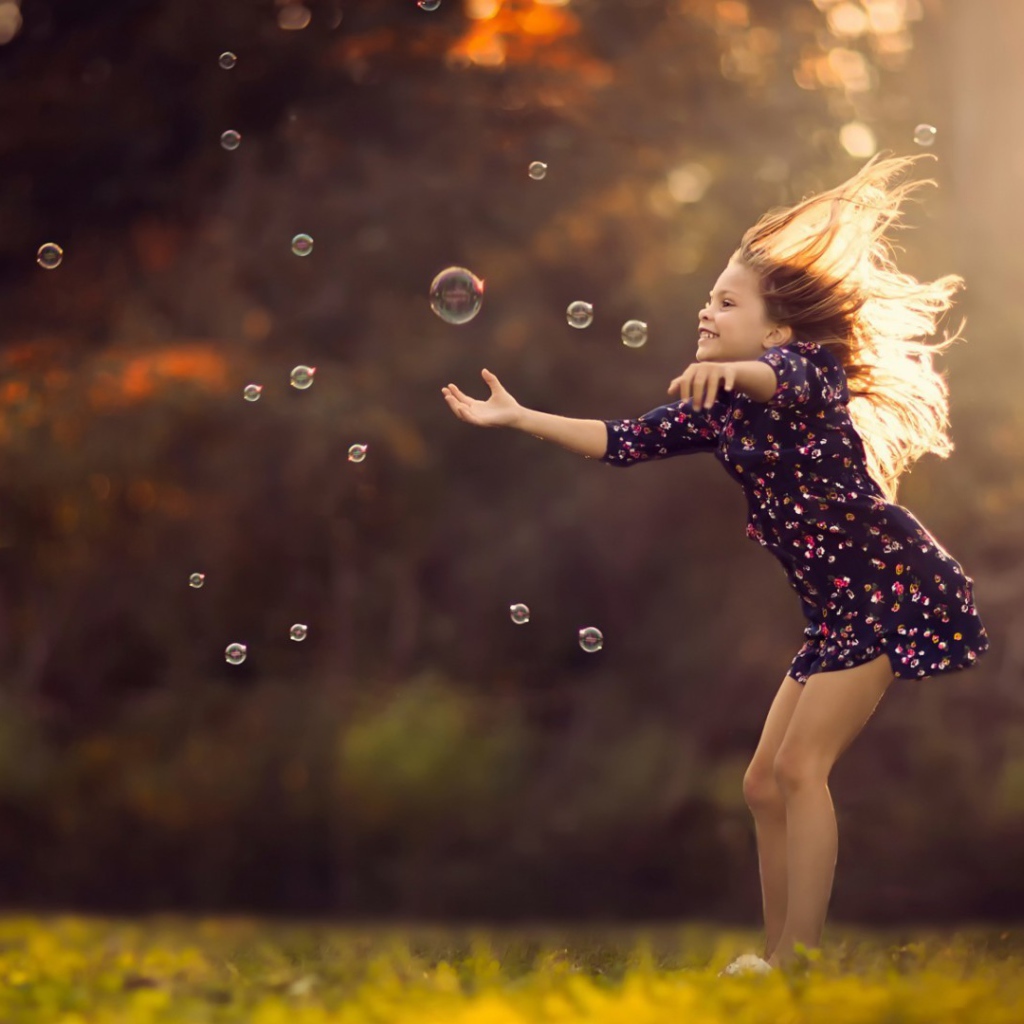 Девочка играет с мыльными пузырями